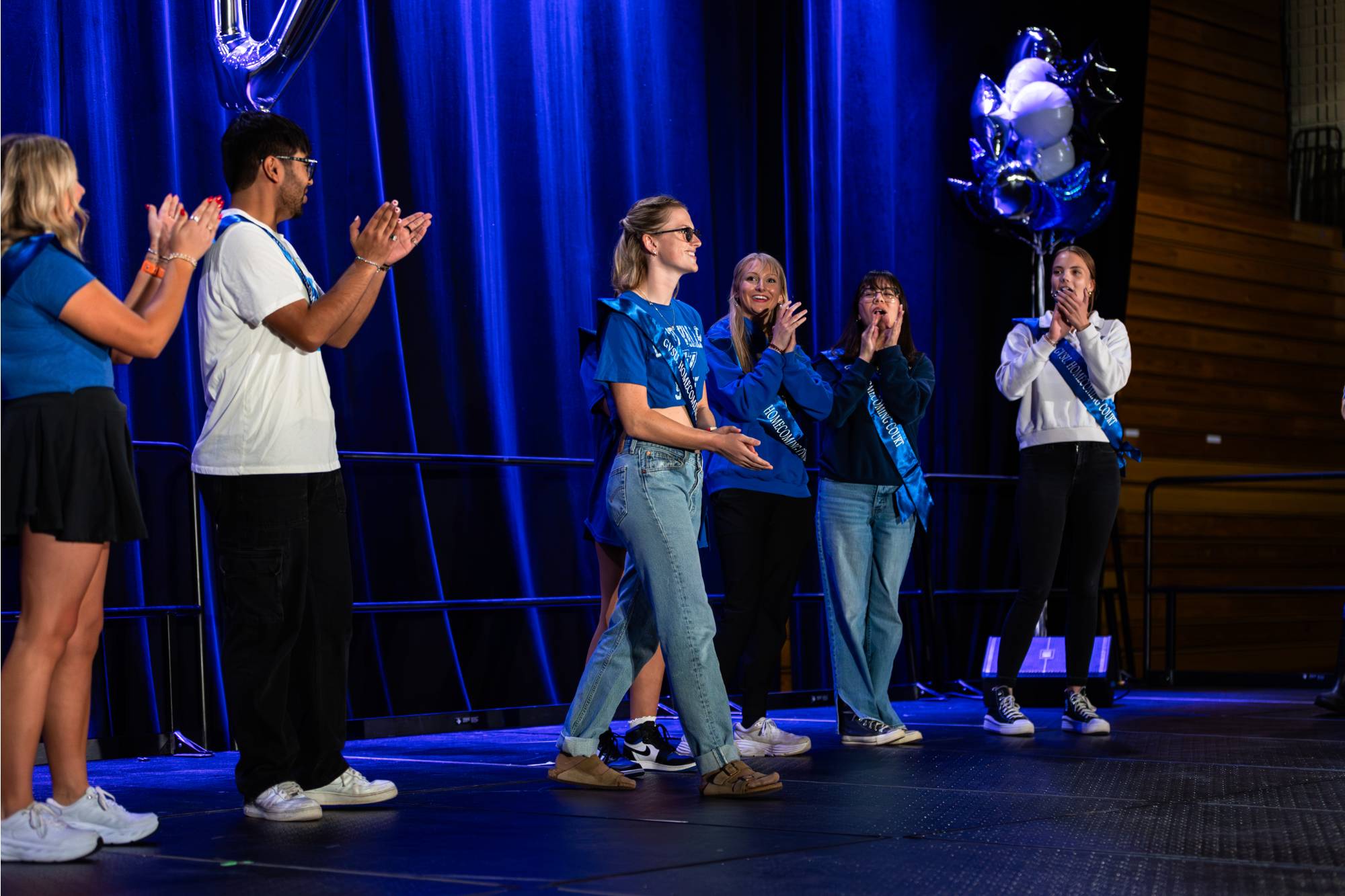 students standing in line as female student walks forward to accept crown